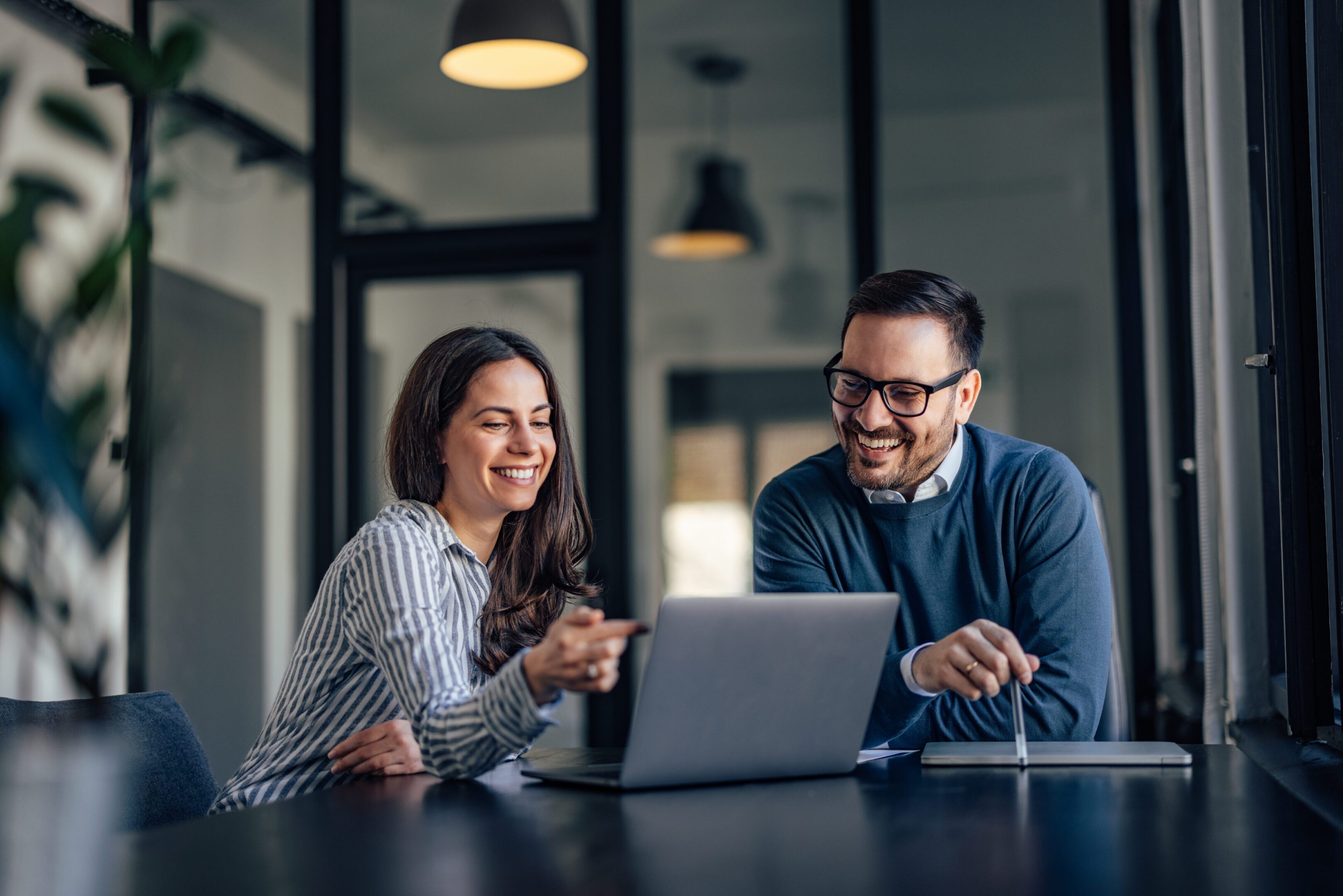 Smiling brunette girl, showing something online to her boss.